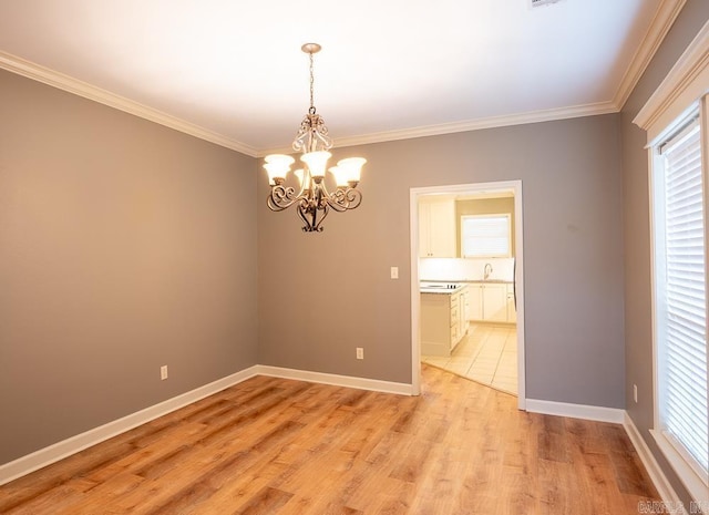 empty room featuring ornamental molding, a chandelier, and light hardwood / wood-style flooring