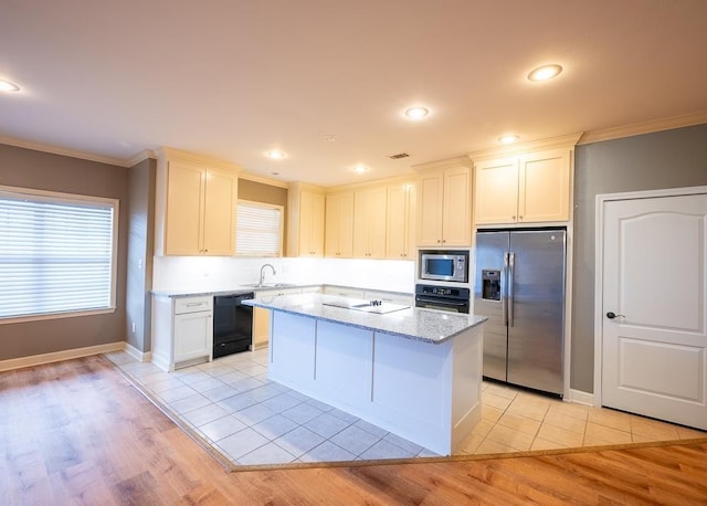 kitchen with a center island, black appliances, sink, light stone counters, and white cabinets