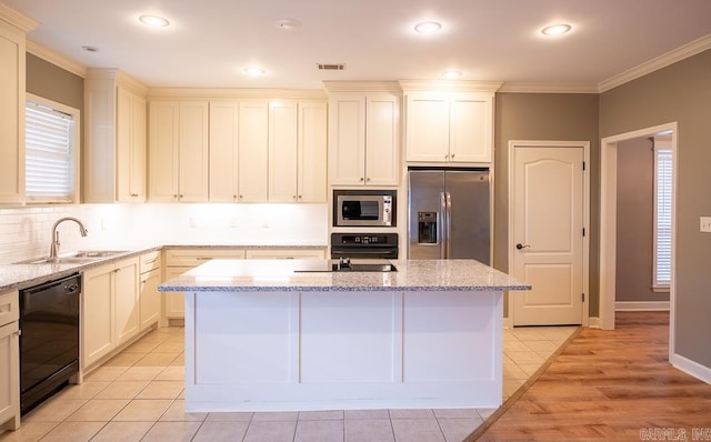 kitchen with a center island, appliances with stainless steel finishes, and light stone counters