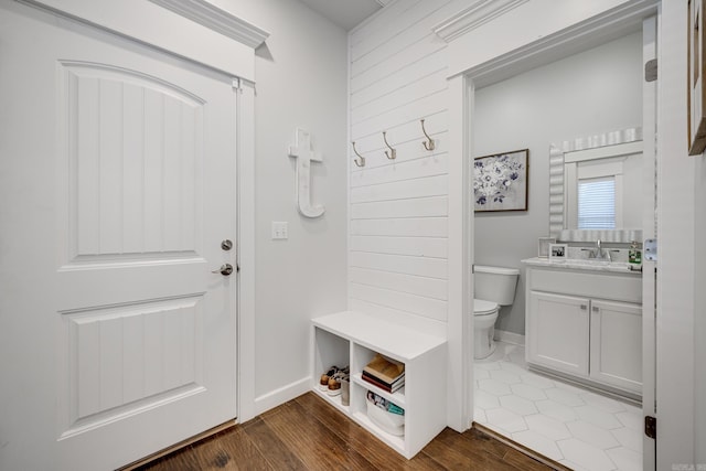 mudroom with dark wood-style floors, a sink, and baseboards