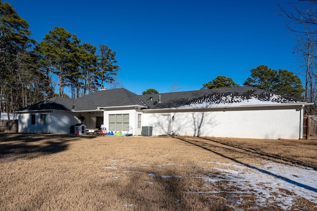 view of front of property with central AC, a lawn, and brick siding