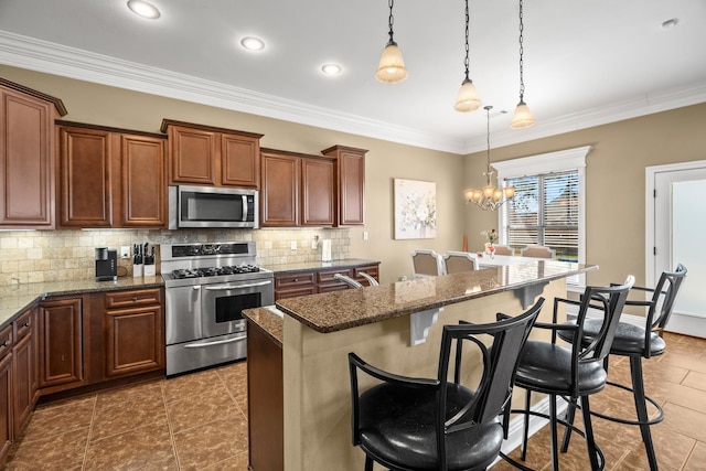 kitchen with appliances with stainless steel finishes, dark stone counters, pendant lighting, a breakfast bar, and a kitchen island