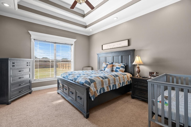 bedroom featuring a raised ceiling, ceiling fan, light carpet, and crown molding