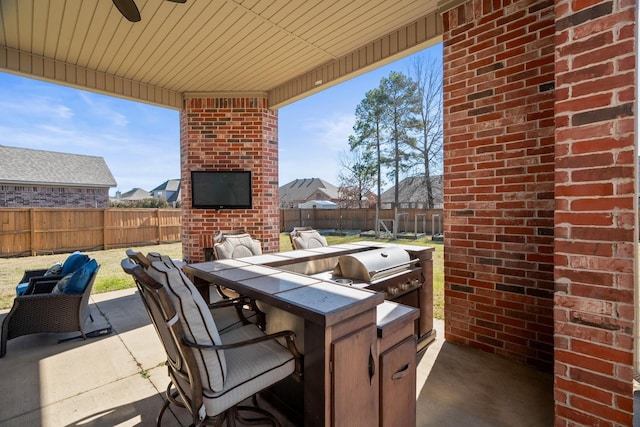 view of patio featuring ceiling fan, area for grilling, a bar, and an outdoor brick fireplace