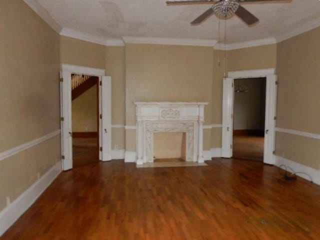 unfurnished living room with ornamental molding, hardwood / wood-style flooring, ceiling fan, and a premium fireplace