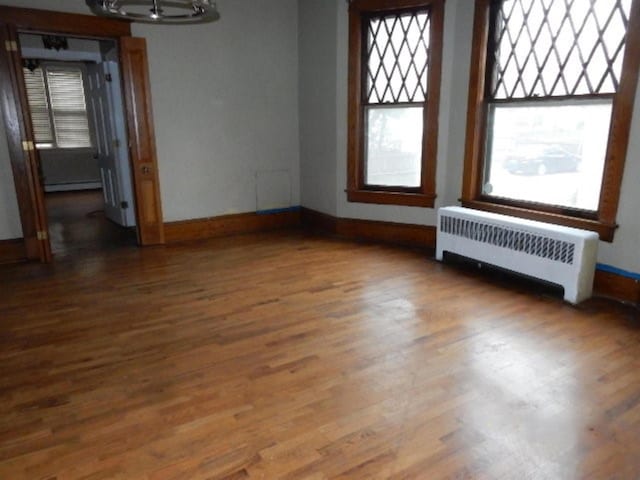 unfurnished room with radiator heating unit, baseboard heating, and dark hardwood / wood-style floors