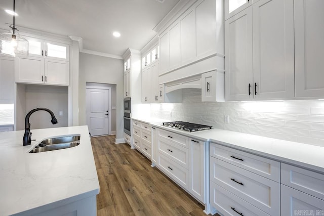 kitchen featuring sink, white cabinetry, crown molding, hanging light fixtures, and tasteful backsplash