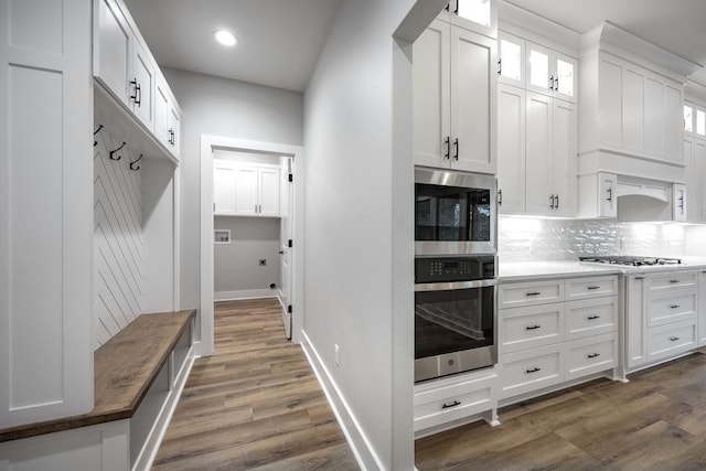 kitchen featuring white cabinetry, built in microwave, stainless steel oven, dark hardwood / wood-style flooring, and decorative backsplash