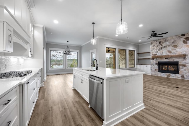 kitchen with sink, stainless steel appliances, white cabinets, hanging light fixtures, and a kitchen island with sink