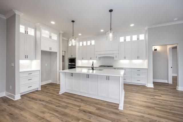 kitchen with sink, white cabinetry, a kitchen island with sink, and crown molding