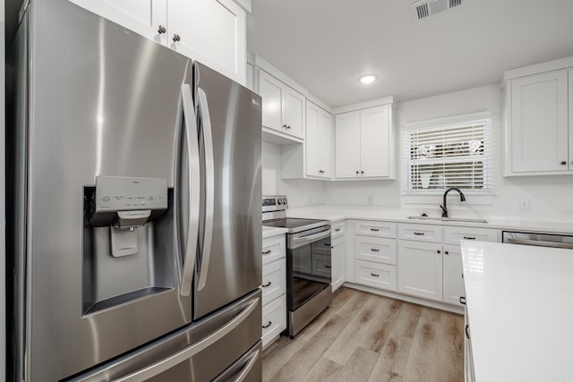 kitchen with sink, stainless steel appliances, white cabinets, and light hardwood / wood-style floors