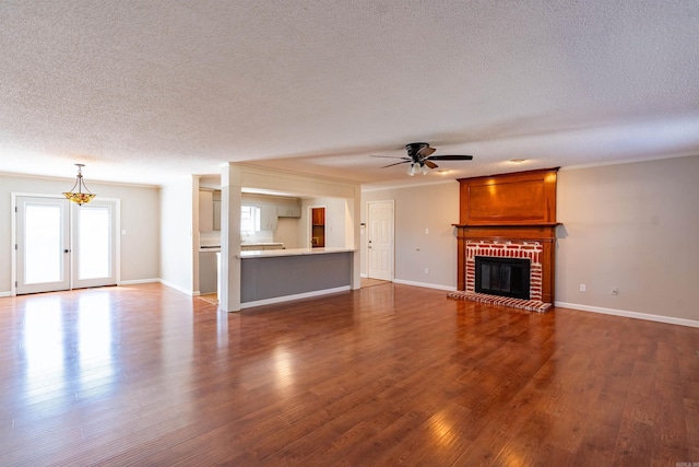 unfurnished living room featuring a textured ceiling, ceiling fan, crown molding, a fireplace, and dark hardwood / wood-style flooring