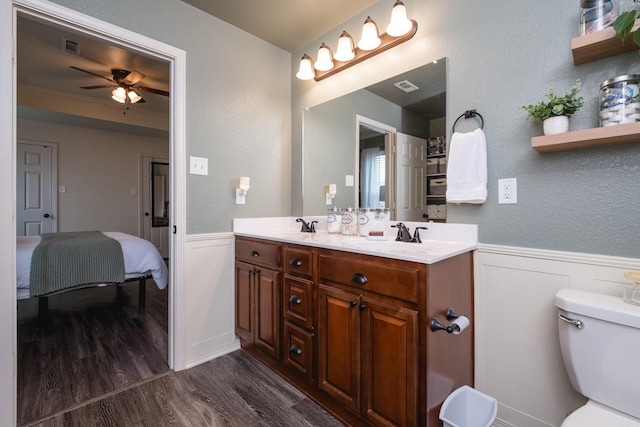 bathroom with toilet, vanity, hardwood / wood-style floors, and ceiling fan