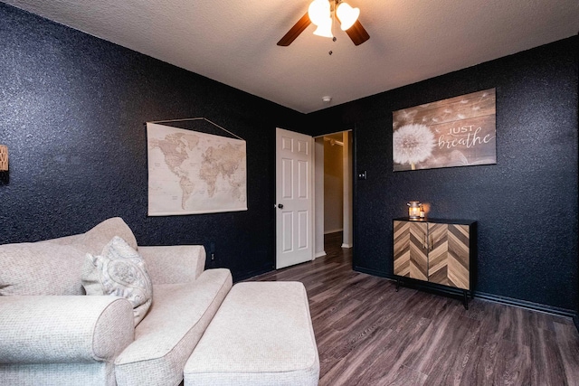 living area with ceiling fan, dark wood-type flooring, and a textured ceiling