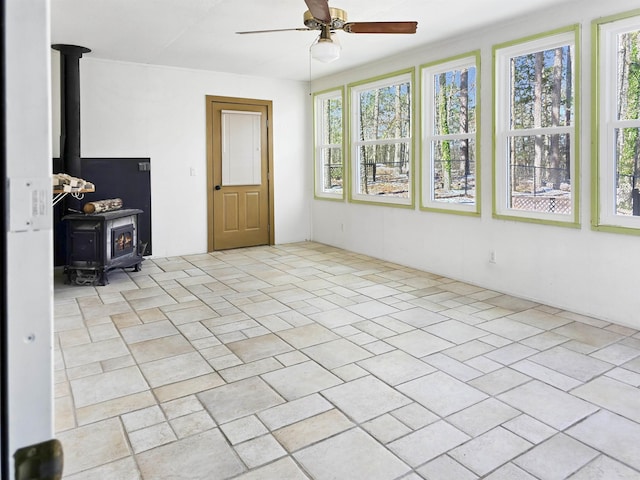 interior space featuring plenty of natural light, a wood stove, and a ceiling fan