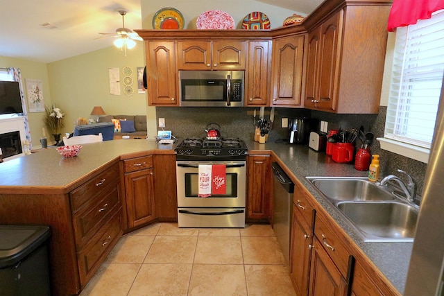 kitchen with appliances with stainless steel finishes, sink, light tile patterned floors, lofted ceiling, and decorative backsplash