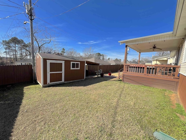 view of yard featuring ceiling fan, a wooden deck, and a storage shed