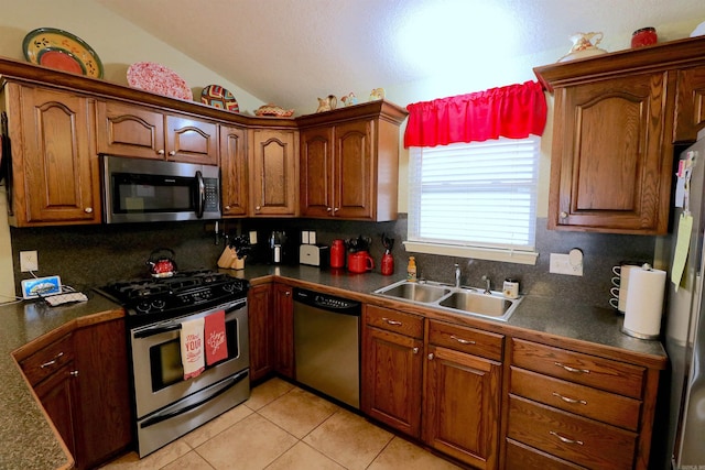 kitchen featuring lofted ceiling, stainless steel appliances, sink, tasteful backsplash, and light tile patterned floors