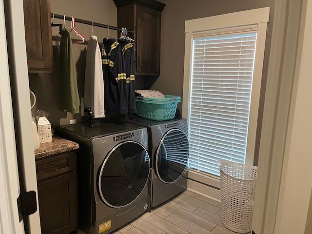 washroom featuring washer and dryer, cabinets, and light wood-type flooring