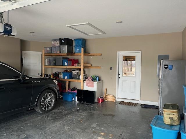 garage featuring a garage door opener and stainless steel fridge