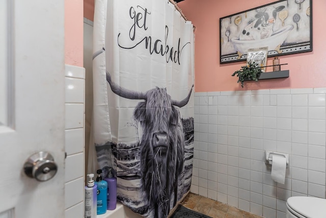 bathroom featuring toilet, tile walls, and a shower with shower curtain