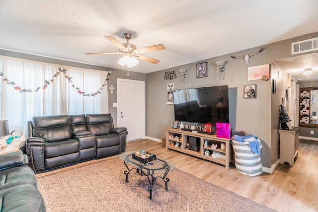 living room with a textured ceiling, ceiling fan, and wood-type flooring