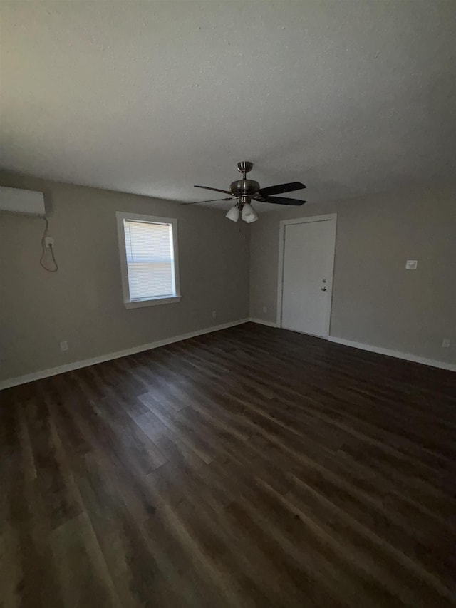 empty room with a wall mounted air conditioner, ceiling fan, dark hardwood / wood-style flooring, and a textured ceiling