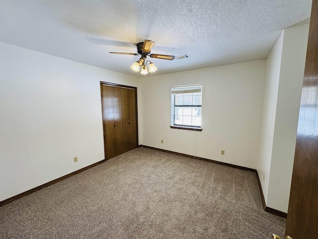 unfurnished bedroom with a textured ceiling, a closet, carpet flooring, and ceiling fan