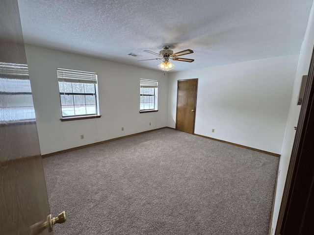 carpeted empty room with ceiling fan and a textured ceiling