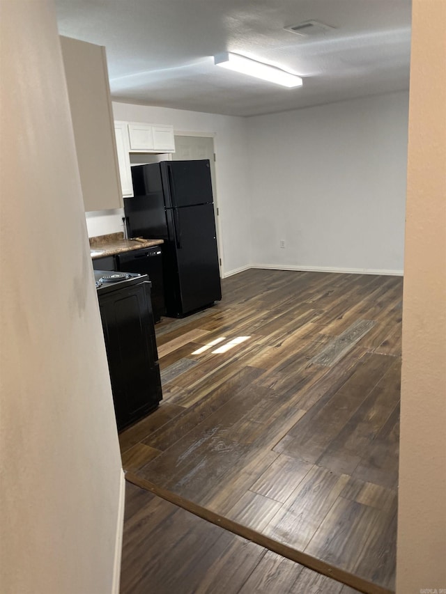 kitchen featuring white cabinetry, range, dark hardwood / wood-style floors, and black fridge