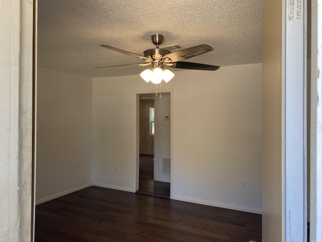 spare room featuring a textured ceiling, dark wood-type flooring, and ceiling fan