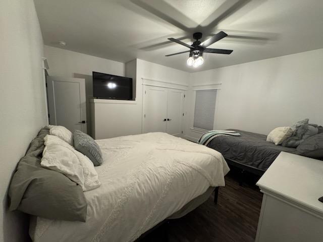 bedroom with dark wood-type flooring, a closet, and a ceiling fan