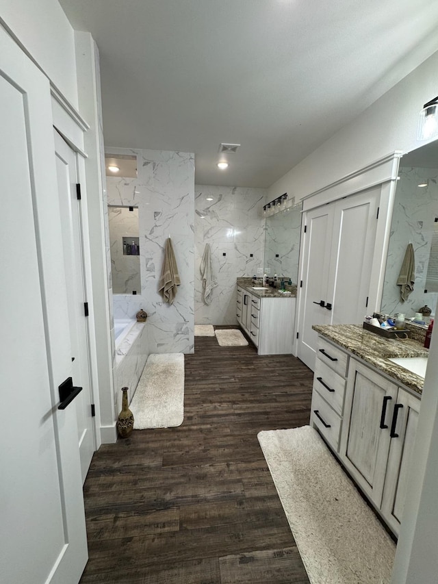 full bath with a sink, two vanities, wood finished floors, visible vents, and a marble finish shower