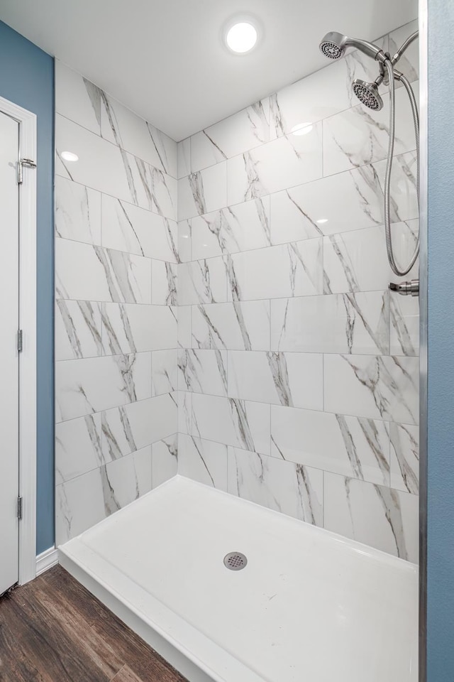 bathroom with a tile shower and wood-type flooring