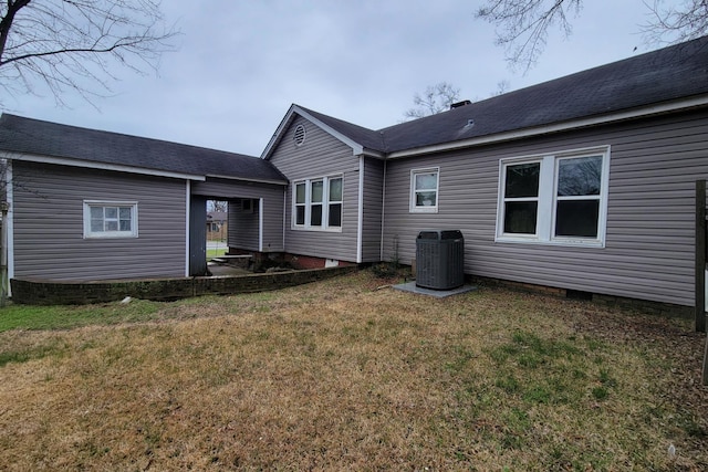 rear view of house featuring central AC unit and a lawn