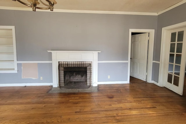 unfurnished living room featuring hardwood / wood-style floors, an inviting chandelier, ornamental molding, and a fireplace