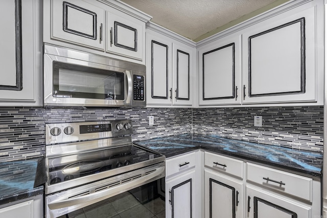 kitchen featuring appliances with stainless steel finishes, white cabinetry, dark stone counters, a textured ceiling, and tasteful backsplash