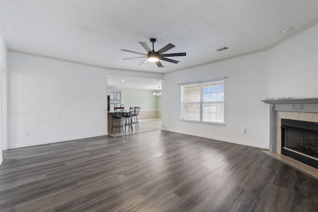 unfurnished living room featuring a fireplace, ornamental molding, dark hardwood / wood-style floors, and ceiling fan with notable chandelier