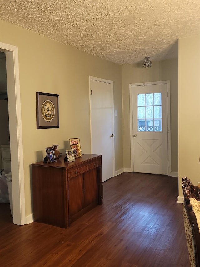 foyer entrance with dark hardwood / wood-style flooring and a textured ceiling