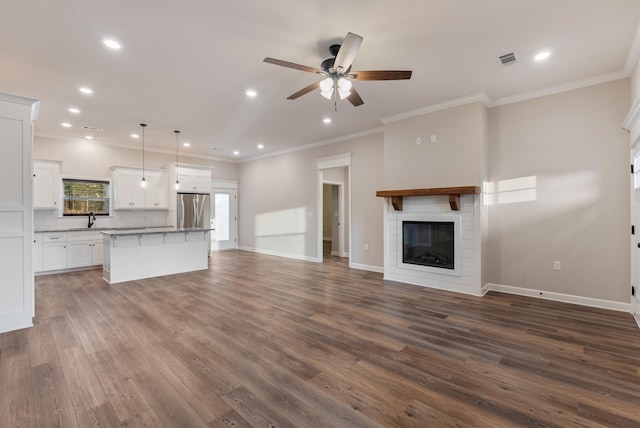 unfurnished living room with sink, dark wood-type flooring, ornamental molding, and ceiling fan