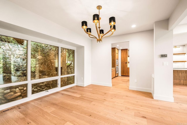 unfurnished dining area featuring visible vents, an inviting chandelier, baseboards, and light wood-type flooring