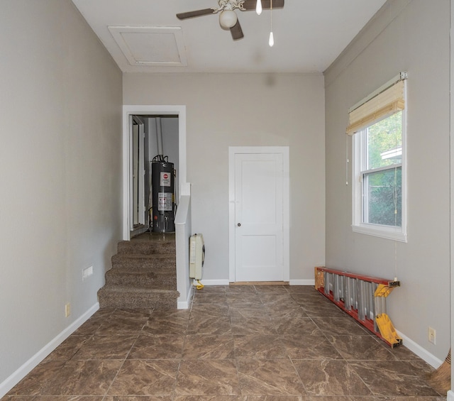 spare room with attic access, water heater, and baseboards