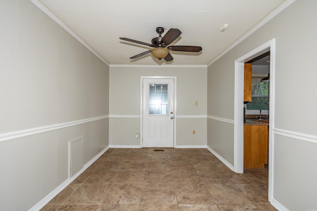 empty room with ceiling fan, visible vents, baseboards, and crown molding