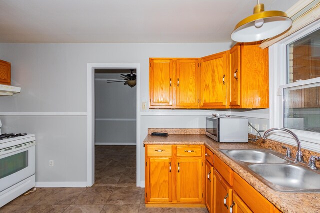 kitchen with gas range gas stove, light countertops, stainless steel microwave, a sink, and under cabinet range hood