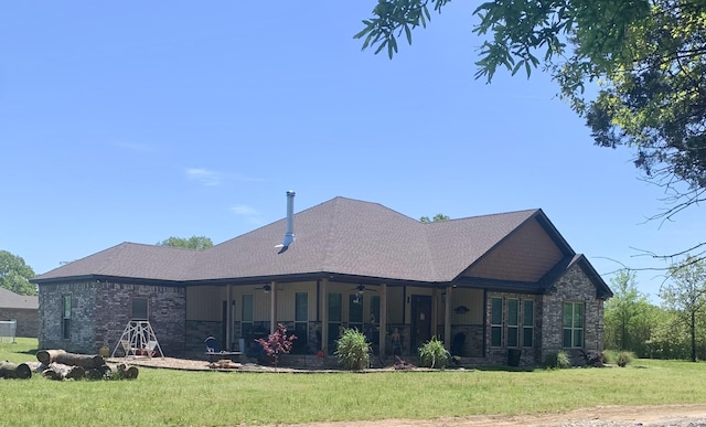 rear view of house with a yard, stone siding, ceiling fan, and a shingled roof