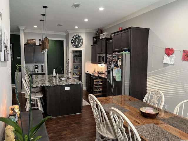 kitchen with a sink, visible vents, appliances with stainless steel finishes, light stone countertops, and an island with sink