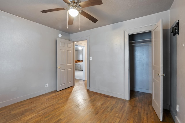 unfurnished bedroom with a ceiling fan, a closet, baseboards, and wood finished floors