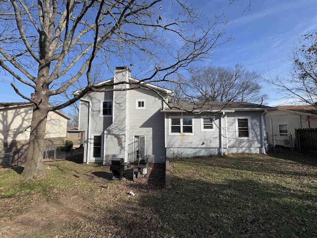 back of house with a chimney, fence, and a lawn