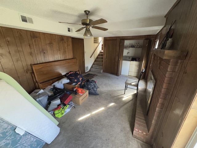 bedroom with wooden walls, washing machine and dryer, visible vents, and light colored carpet