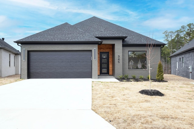 view of front facade with concrete driveway, roof with shingles, brick siding, and an attached garage